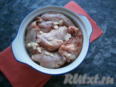 Кролика порубить на небольшие части, посолить, посыпать специями для мяса и выложить сверху овощей. Посыпать кусочки кролика пластинами чеснока.