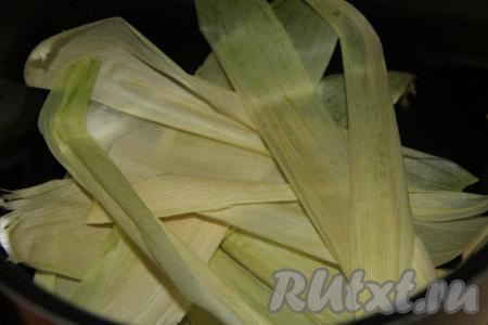 Початки кукурузы очистить от листьев. Часть листьев выложить на дно мультиварки (можно, конечно, готовить и без листьев, но с ними кукуруза получается особенно нежной и ароматной).