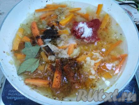 В сковородку к обжаренным овощам добавляем 0,5 стакана воды, томатную пасту, лавровые листы, 1 чайную ложку соли, чёрный молотый перец, приправу для курицы и мелко нарезанные зубчики чеснока.