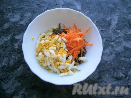 Сырую морковку очистить и натереть на крупной тёрке, яйца нарезать длинными кусочками. Добавить морковку и яйца&nbsp;к морской капусте.