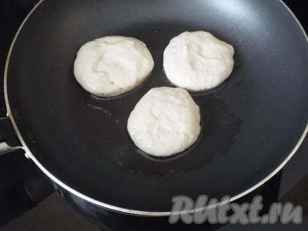 Через указанное время в сковороде (лучше если она будет с антипригарным покрытием) разогрейте 2 столовые ложки растительного масла. Наберите ложкой тесто (ложку предварительно смочите водой), обрежьте тесто&nbsp;о край миски. Выложите тесто на сковороду, формируя оладушек. Жарьте оладьи 3 минуты на огне чуть ниже среднего.