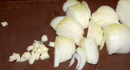 Нарезать чеснок мелкими кусочками, а репчатый лук полукольцами.
