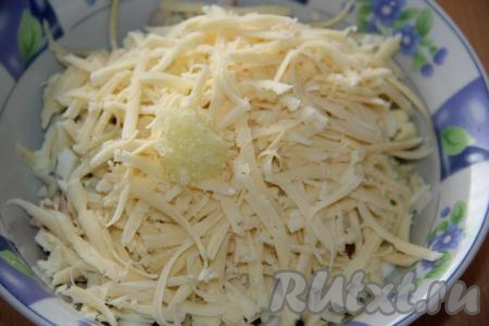 В салат из варёных кальмаров, сыра и яиц добавить пропущенный через пресс зубчик чеснока.