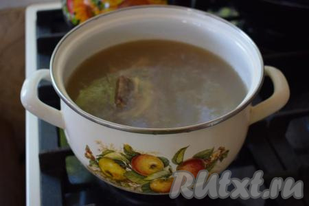 Говяжьи кости промываем под холодной водой и помещаем в кастрюлю. Наливаем в кастрюлю 2 литра воды, кладём очищенную луковицу и очищенный зубчик чеснока. Отправляем кастрюлю на огонь и варим бульон до закипания. Когда бульон начнёт закипать, снимаем пену при помощи ситечка с поверхности бульона. Далее на умеренном огне варим наш бульон до полной готовности мяса (примерно, 1,5-2 часа).