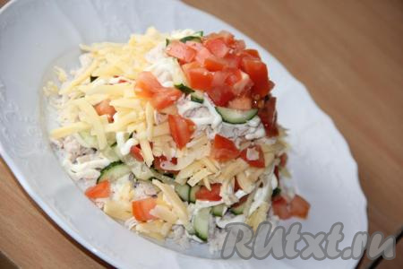 Затем повторить слои, формируя острую верхушку из оставшихся ингредиентов: поверх сыра выложить оставшееся куриное мясо, нанести сеточку из смеси майонеза и чеснока, выложить брусочки свежего огурца и оставшийся помидор.