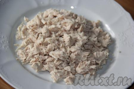 Кусочек курицы (я взяла куриное филе) предварительно отварить до готовности в подсоленной воде (на это потребуется минут 25-30 с начала кипения воды), остудить. 200 грамм отваренного куриного мяса нарезать на небольшие кусочки (или порвать на волокна). 2/3 куриного мяса выложить на тарелку - это будет первый слой салата.