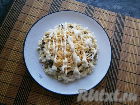 Теперь выкладываем натёртый на крупной тёрке сыр, наносим майонезную сеточку.