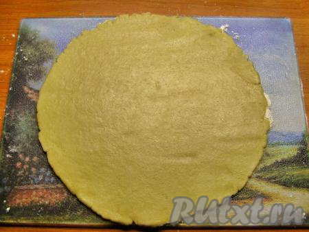 Достаём тесто из холодильника и на присыпанной мукой доске раскатываем из теста круг, диаметр которого должен быть немного больше диаметра формы для выпечки.