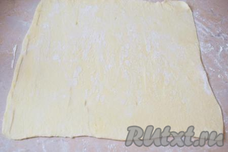 Для приготовления рулета можно использовать любое слоёное тесто - дрожжевое или бездрожжевое. Слоёное тесто обычно продаётся в замороженном виде, поэтому ему необходимо предварительно дать оттаять. Заранее достаньте его из морозильной камеры и дайте полежать при комнатной температуре. Стол присыпьте мукой. Мягкое тесто с помощью скалки, присыпанной мукой, немного раскатайте в прямоугольник.