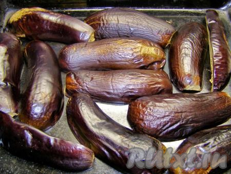 Выкладываем половинки баклажанов на противень и также запекаем в разогретой духовке при температуре 180-200 градусах около 20 минут (пока кожица не сморщится). Горячие баклажаны кладём в кастрюлю, накрываем крышкой (или в пакет и завязываем его) и оставляем немного остыть.