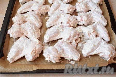 Противень застелите кулинарной бумагой и разложите крылышки в один слой, равномерно распределяя их по всей поверхности. Поставьте противень в духовку, разогретую до 190 градусов, на 30-40 минут. Ориентируйтесь по своей духовке.