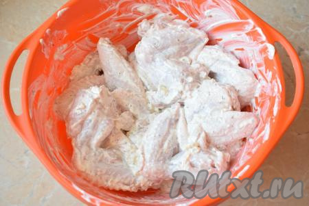 В сметанный маринад выложите куриные крылышки. Хорошо обваляйте крылышки в маринаде, стараясь, чтобы они были им покрыты со всех сторон. Оставьте постоять при комнатной температуре на 1-2 часа.