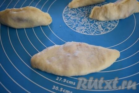 Далее переворачиваем пирожки швом вниз и слегка прижимаем к столу, придавая плоскую форму.