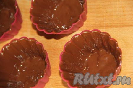 Нанести шоколад с помощью силиконовой кисточки в два слоя на стенки каждой силиконовой формочки&nbsp;и поставить в морозилку минут на 15-20 (до полного застывания шоколада). Часть растопленного шоколада оставить для нанесения в дальнейшем поверх творожной массы.