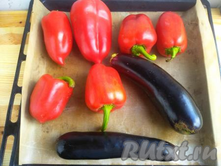 Противень застелить антипригарным ковриком для выпечки (или пергаментом). Вымыть болгарские перцы и баклажаны. У баклажанов отрезать хвостики. Выложить болгарские перцы и баклажаны на застеленный противень, отправить в разогретую духовку и запекать около 30 минут при температуре 200 градусов. В процессе запекания (через 15 минут) овощи перевернуть. Овощи должны стать мягкими и легко протыкаться вилкой.