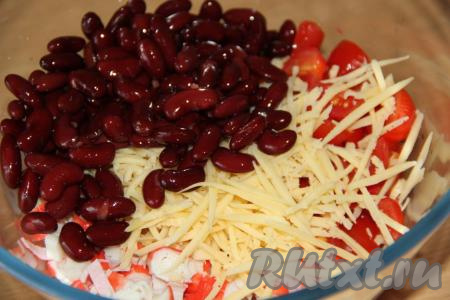 С консервированной фасоли слить жидкость. Сыр, натёртый на крупной тёрке, и фасоль выложить в салат из крабовых палочек и помидоров.