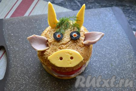 Теперь остаётся самое интересное - украшение. По бокам верхней булочки сделать ножом отверстия и вставить ломтики колбасы в виде ушек. Рожки и нос вырезать из сыра. Ноздри можно вырезать с помощью трубочки. Вверху булочки также сделать разрезы и вставить рожки. Глазки сделать из кружочков черной оливки, в серединку капнуть майонезом и кетчупом. Веточку укропа разместить в виде чубчика.