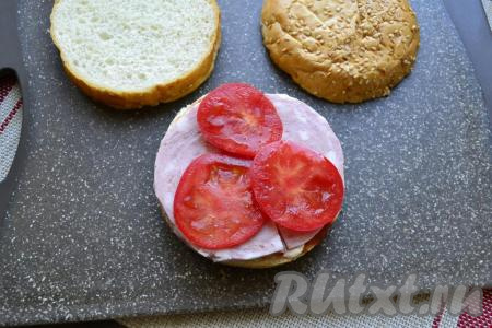 Далее выложить колбасу по диаметру булочки (можно колбасу выкладывать из 2-х ломтиков). На колбасе разместить тонкие кружочки свежего помидора.