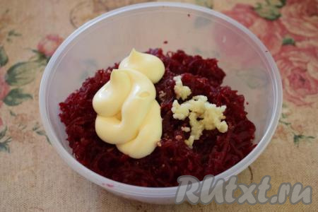 Далее натёртую свеклу солим, перчим и кладём к ней майонез. Чеснок выдавливаем через пресс и также отправляем к свекле.