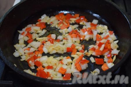 Сковороду ставим на огонь и вливаем в неё растительное масло. В разогретое масло кладём нарезанные лук, чеснок и болгарский перец, жарим&nbsp;до подрумянивания овощей на среднем огне, помешивая.