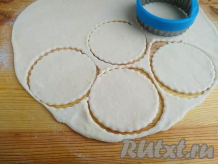 На столе, присыпанном мукой, раскатать тесто в пласт толщиной 2 мм. Выемкой (или стаканом) диаметром около 9-10 см вырезать кружки.