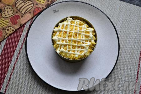 Сверху выложить варёный желток, натёртый на тёрке, на который нанести сеточку из майонеза.