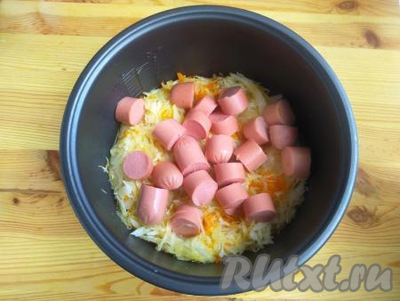 Сосиски разрезать на 6-7 частей, выложить поверх капусты.