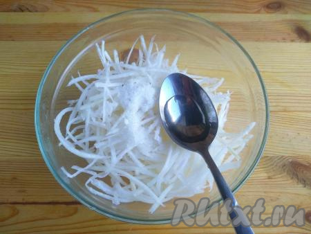 По истечении 10 минут откинуть дайкон на дуршлаг, дать стечь лишней жидкости. Затем выложить дайкон в миску для приготовления салата, добавить соль, сахар и оставшийся уксус, перемешать, оставить на 5-7 минут при комнатной температуре.