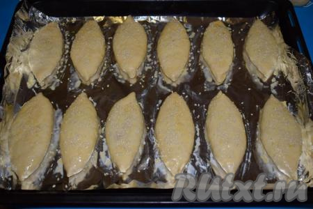 Сверху дрожжевые пирожки с капустой присыпаем кунжутом (я использовала белый и чёрный кунжут).