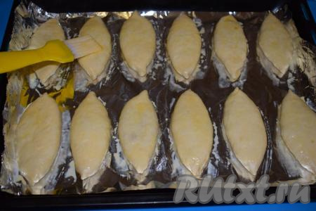 Подготовленные пирожки выкладываем на противень, застеленный пергаментом (или фольгой). Смазываем пирожки сырым яйцом, размешанным до однородности при помощи вилки.