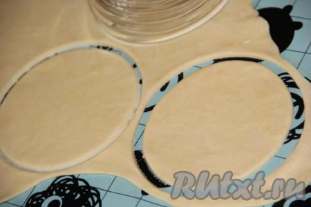 Тесто достать из пакета и на поверхности, слегка присыпанной мукой, тонко раскатать скалкой в пласт. С помощью большого стакана (или круглой формы) вырезать кружочки.