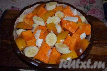 Далее в пустоты между кусочками тыквы раскладываем хурму и банан. Посыпаем десерт ванильным сахаром и вливаем воду.