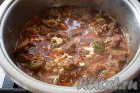 Вливаем ещё немного воды, если жидкость во время тушения выпарилась.&nbsp;Добавляем очищенный чеснок, пропущенный через пресс, и посыпаем блюдо зеленью. Даём говядине с овощами закипеть.