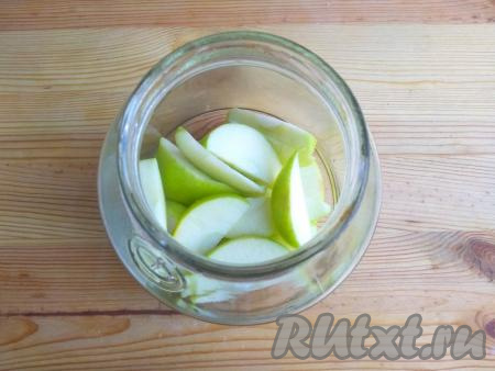 Банку вымыть с пищевой содой, хорошо сполоснуть в прохладной воде, простерилизовать любым удобным для вас способом. Крышку прокипятить в воде в течение минуты. Яблоко вымыть, очистить от сердцевины, а затем нарезать на дольки толщиной 5-7 мм и выложить на дно банки.