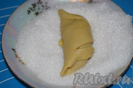 У меня получилось 34 рогалика (32 штуки из раскатанного теста + 2 штуки из обрезков). Далее насыпаем сахар в плоскую тарелку и обваливаем каждый рогалик в сахаре с верхней стороны.