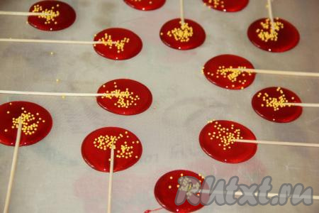 Набрать в чайную ложку карамель и вылить её на силиконовый (или тефлоновый) коврик в виде кружочка. Сразу вставить деревянную шпажку и посыпать цветной посыпкой. Таким образом, используя всю карамель, сваренную с добавлением глюкозного сиропа, сформировать все леденцы на палочках. Оставить леденцы до полного застывания (минут на 20).