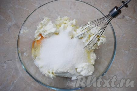 Затем к творогу и яйцам добавьте сахар (количество сахара можно по своему вкусу немного уменьшить или увеличить), перемешайте с помощью венчика (или разомните вилкой до однородности).
