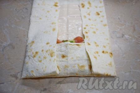 Накройте начинку частью лаваша, после этого подверните края лаваша с двух сторон (как на фото) и сворачивайте лаваш рулетом. Немного прижимайте, делая рулет плоским.
