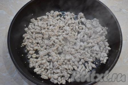 Для приготовления начинки возьмите глубокую сковороду, разогрейте её до горячего состояния, влейте немного растительного масла и выложите фарш. Обжарьте фарш на среднем огне 5-7 минут, не забывая перемешивать.