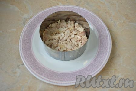 Начинайте собирать салат. Для этого можно использовать любой салатник или же, как у меня, сервировочное кольцо для порционной подачи. Куриное мясо нарежьте на мелкие кусочки и выложите первым слоем. Этот слой и все последующие смажьте небольшим количеством майонеза.