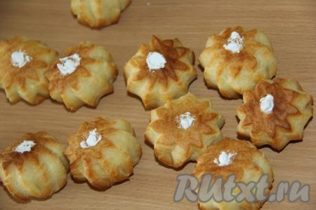 Проколоть насадкой дно профитролей и наполнить взбитыми сливками.