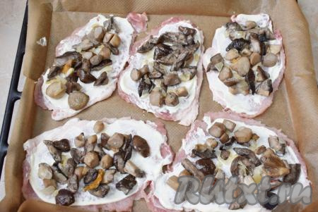 Затем поверх смазанных отбивных равномерно распределите обжаренные грибы с луком.