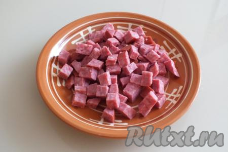 Полукопчёную колбасу нарежьте на кубики со стороной 1 см.