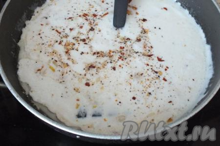 В сковороду с обжаренным луком, добавьте сметану, 100 мл кипячёной воды, соль и молотый чёрный перец по вкусу, перемешайте, поставьте на средний огонь и доведите сметанный соус до кипения.