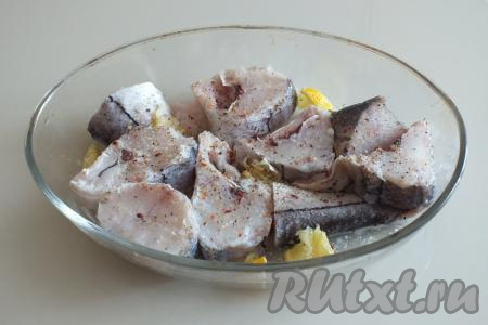 Возьмите просторную миску, переложите в неё пикшу. Сверху выдавите лимонный сок, добавьте по вкусу соль и чёрный молотый перец, перемешайте. Отставьте на время, пока будет обжариваться лук.