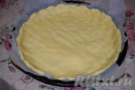 По прошествии времени застилаем форму диаметром 24 см пергаментом. Распределяем тесто по всей поверхности, формирую бортики.