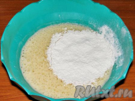 Всыпаем немного просеянной муки и перемешиваем ложкой. Затем частями добавляем остальную муку и руками замешиваем тесто. Обратите внимание на то, что муки может понадобиться немного больше или меньше того количества, которое указано в рецепте.