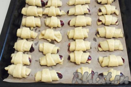 Подготовленные рогалики с повидлом выложите на противень, застеленный пекарской бумагой, и поставьте в разогретую до 190 градусов духовку на 20-25 минут (песочное тесто должно стать приятного золотистого цвета). Продолжительность выпечки во многом зависит от особенностей духовки.