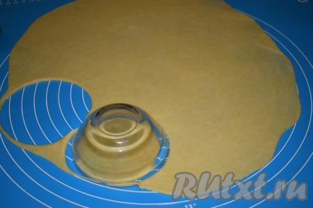 Далее на поверхности, чуть припылённой мукой, раскатываем охлаждённое песочное тесто в пласт толщиной 2-3 мм, затем при помощи пиалы (или стакана) вырезаем кружочки. Для того чтобы было легко сформировать бортики будущих корзиночек, размер вырезанных кружочков должен быть больше диаметра ваших силиконовых формочек.