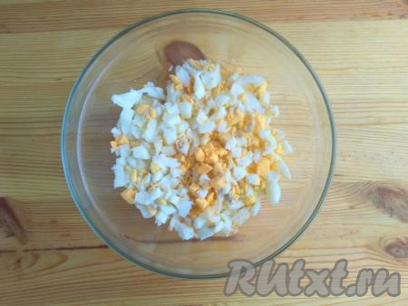 Яйца выложить в небольшую кастрюльку, полностью залить холодной водой, поставить на огонь и довести до кипения, после этого варить на среднем огне 9 минут. Охладить их и очистить от скорлупы. Нарезать яйца небольшими кусочками и выложить к нарезанным ананасам.